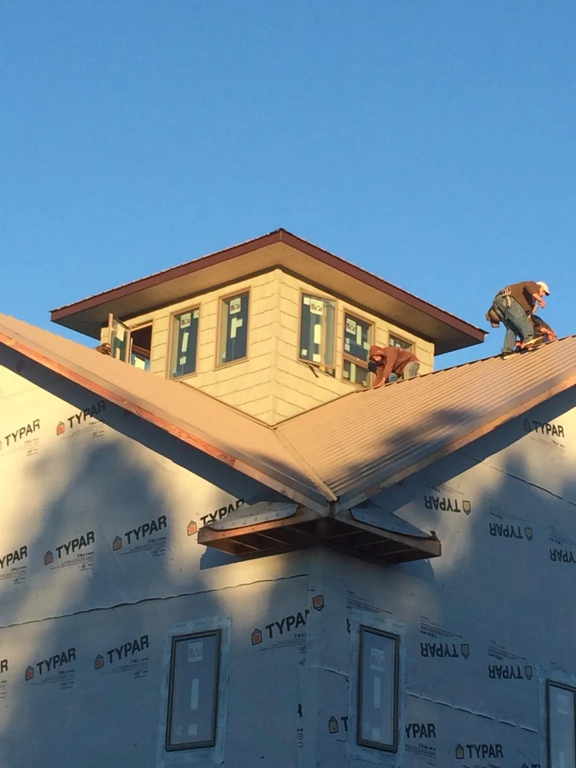 Roofers working around a rooftop cupola on a new metal roof at sunset — Roof Waterproofing in Mount Union by Roofing Brothers